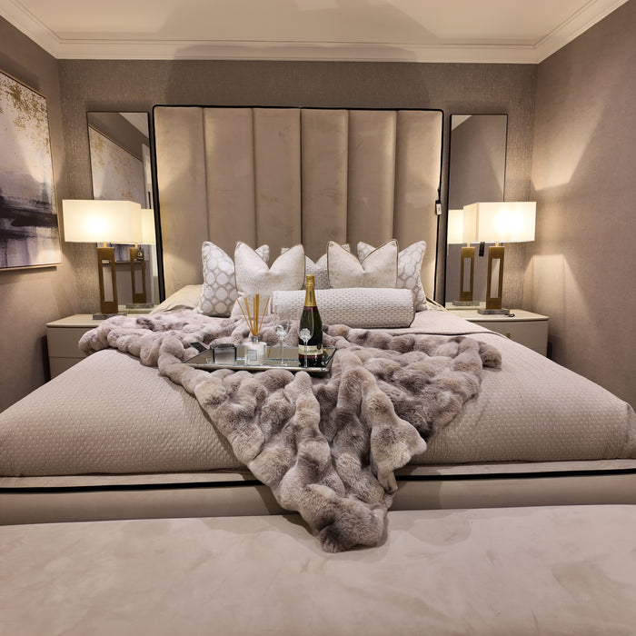 Custom Belle bed with a tall, panelled upholstered headboard in neutral fabric, plus fur throw and mirrored nightstands